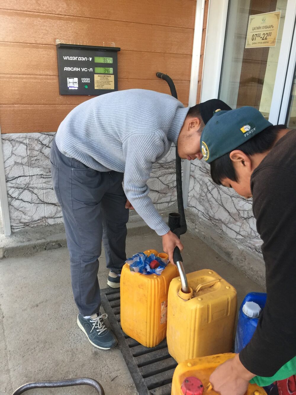 Two residents filling yellow water containers from a smart well